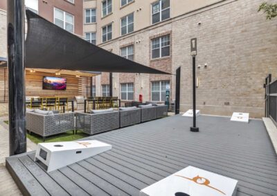 outdoor community area with corn hole and grilling stations